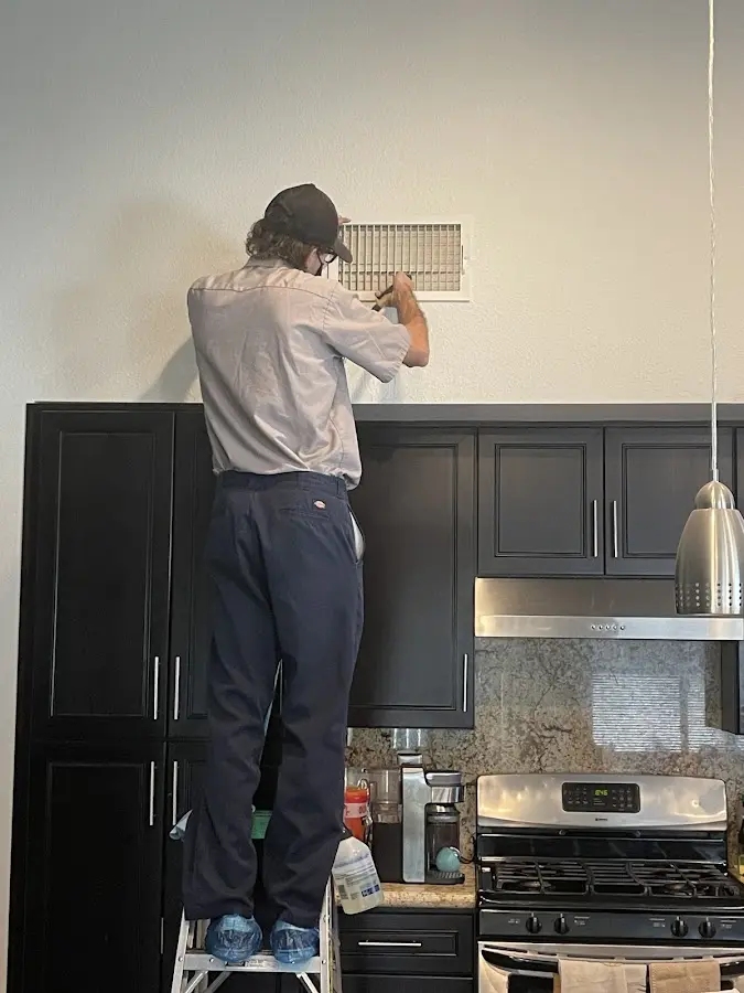 Technician inspecting an air vent during HVAC service in Williamstown